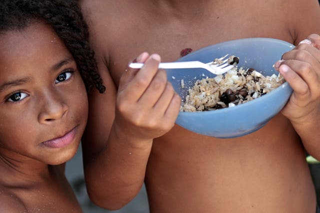 <p>Thawanny Silva de Souza, 6, and Rafael Silva de Souza, 9, eat a lunch of rice, beans and egg in their family’s house, in the Arco Iris favela in Recife, Brazil</p>
