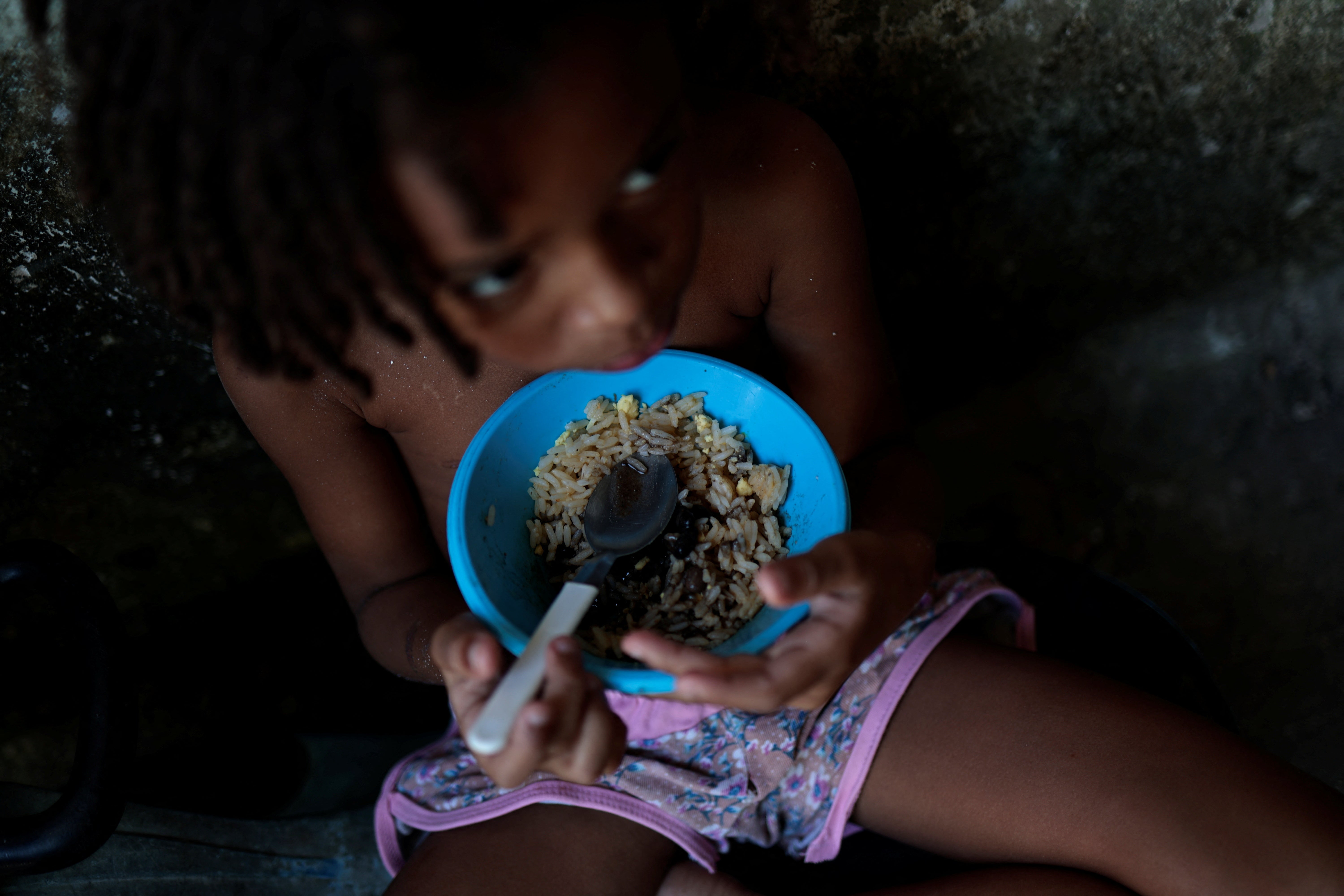Thawanny eats a lunch of rice, beans and egg in her family's house, in the Arco Iris favela