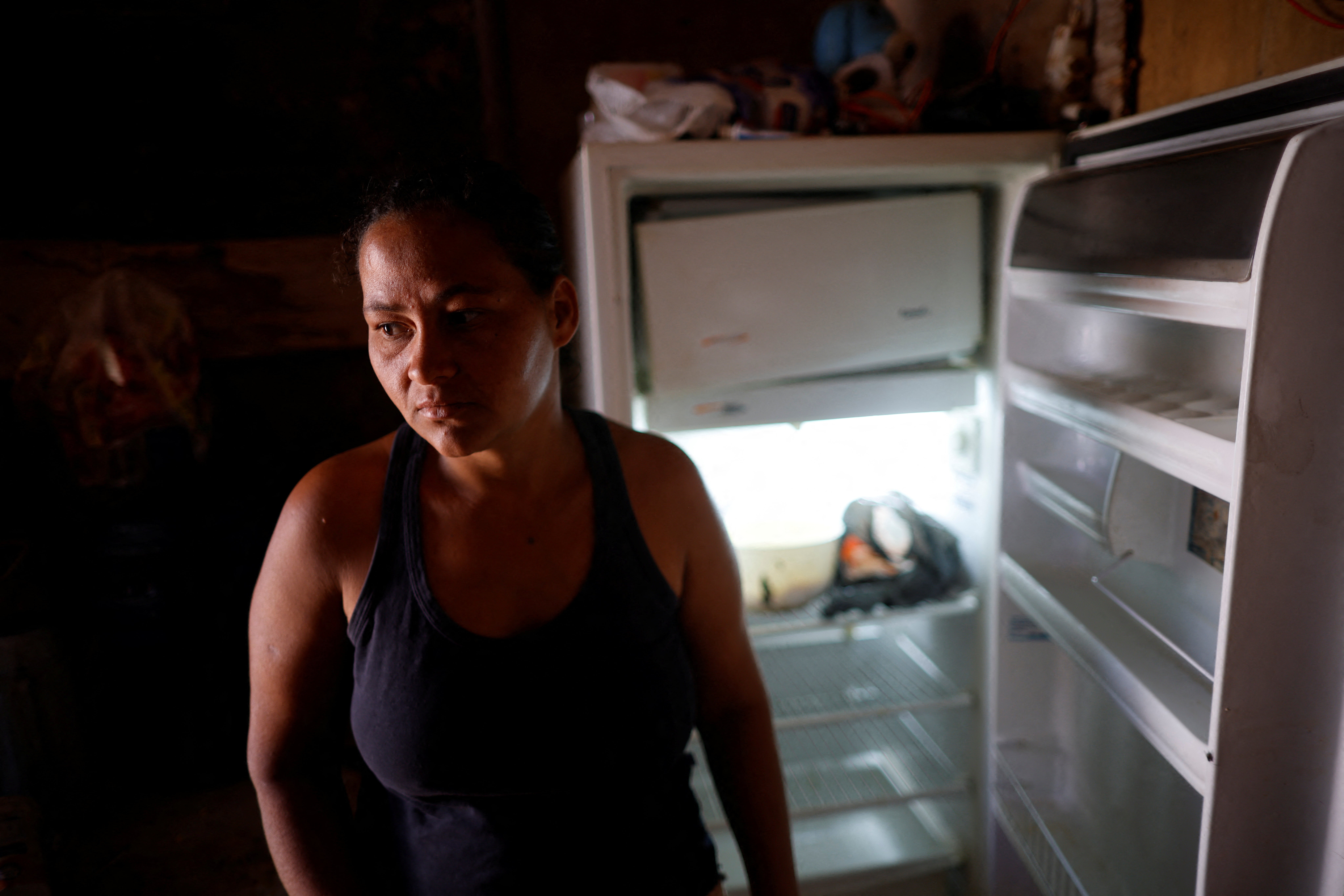 Luciana Messias dos Santos, 29, poses for a picture in front of her empty fridge at her home in the Estrutural favela in Brasilia