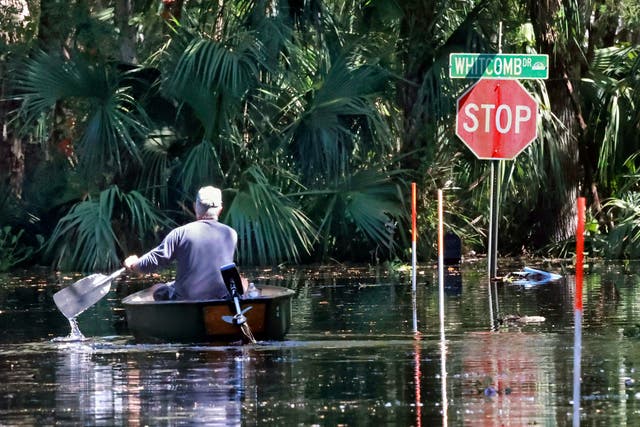 <p>A man canoes through his neighbourhodd in Geneva, Florida, which is still flooded more than a week after Hurricane Ian</p>