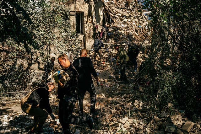 <p>Volunteers remove the rubbles of a building looking for survivors after a strike in Zaporizhzhia on 6 October 2022, amid the Russian invasion of Ukraine</p>