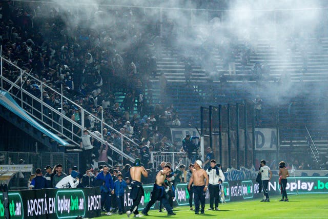 <p>Fans at the Juan Carmelo Zerillo Stadium were forced on to the pitch after tear gas drifted in to the stands </p>