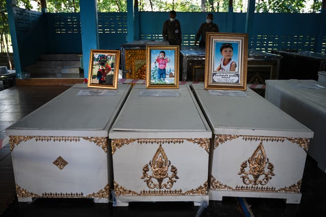 <p>Portraits of victims sit atop coffins at Wat Si Uthai temple</p>