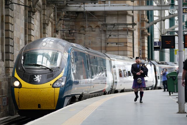 A piper walks the platform alongside the Avanti West Coast Class 390 EMU train as it arrives in Glasgow (Jane Barlow/PA)