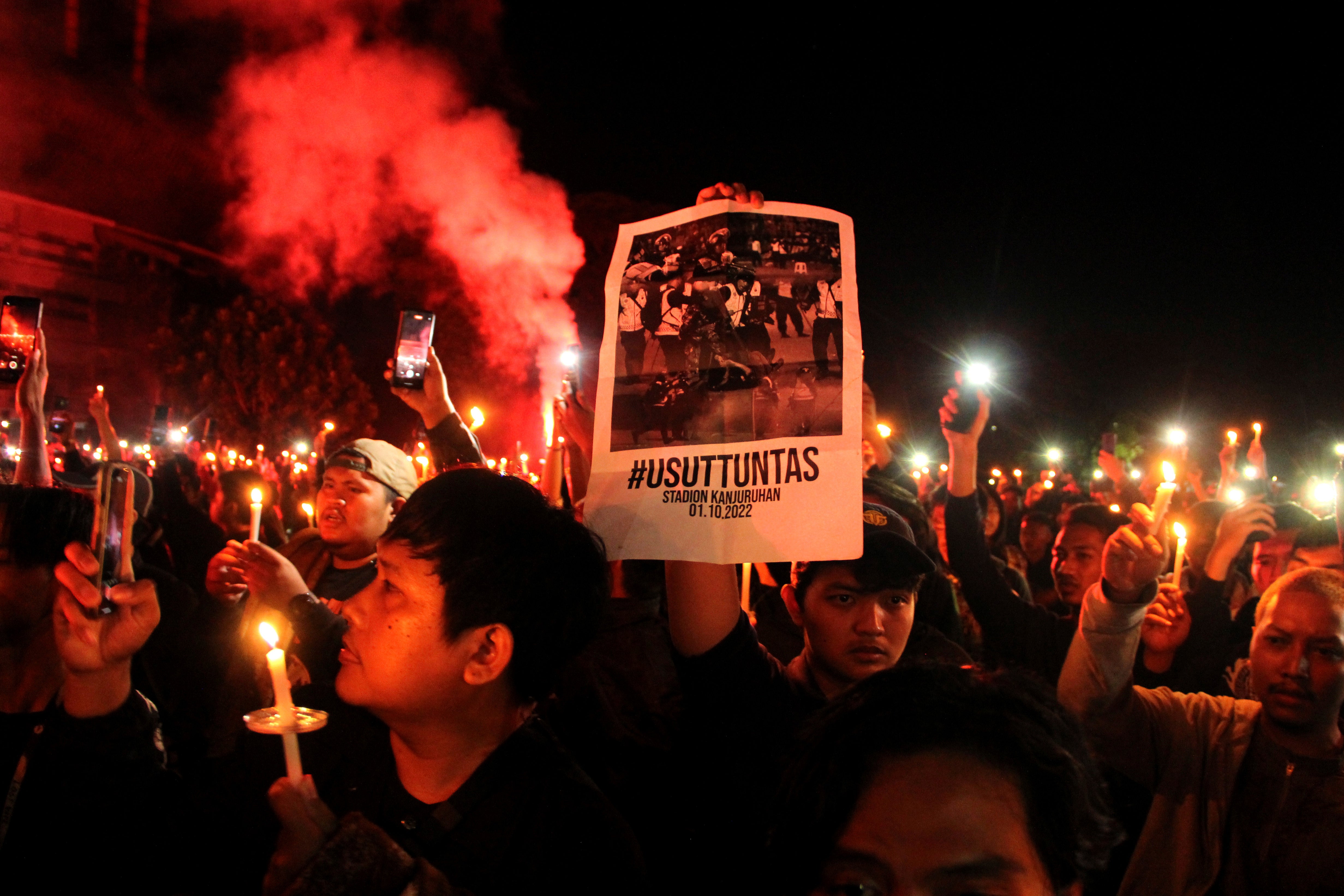 Football fans light a flare during a candle light vigil for the victims