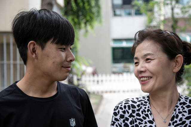 <p>Kim Kang-woo, left, and his mother, Im Su-ryuh, near her apartment in Seoul</p>