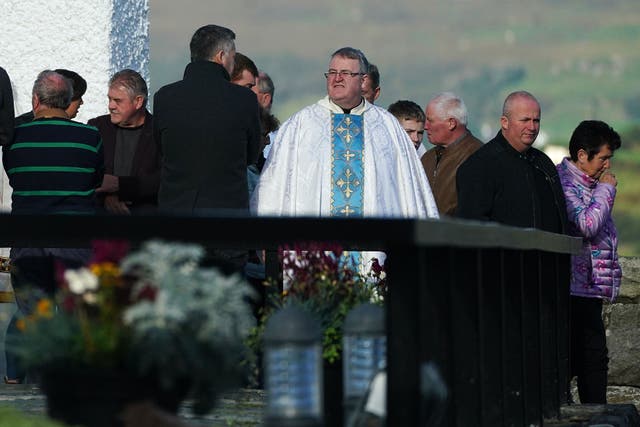 Father John Joe Duffy with members of the public as they leave St Michael’s Church Creeslough (Brian Lawless/PA)