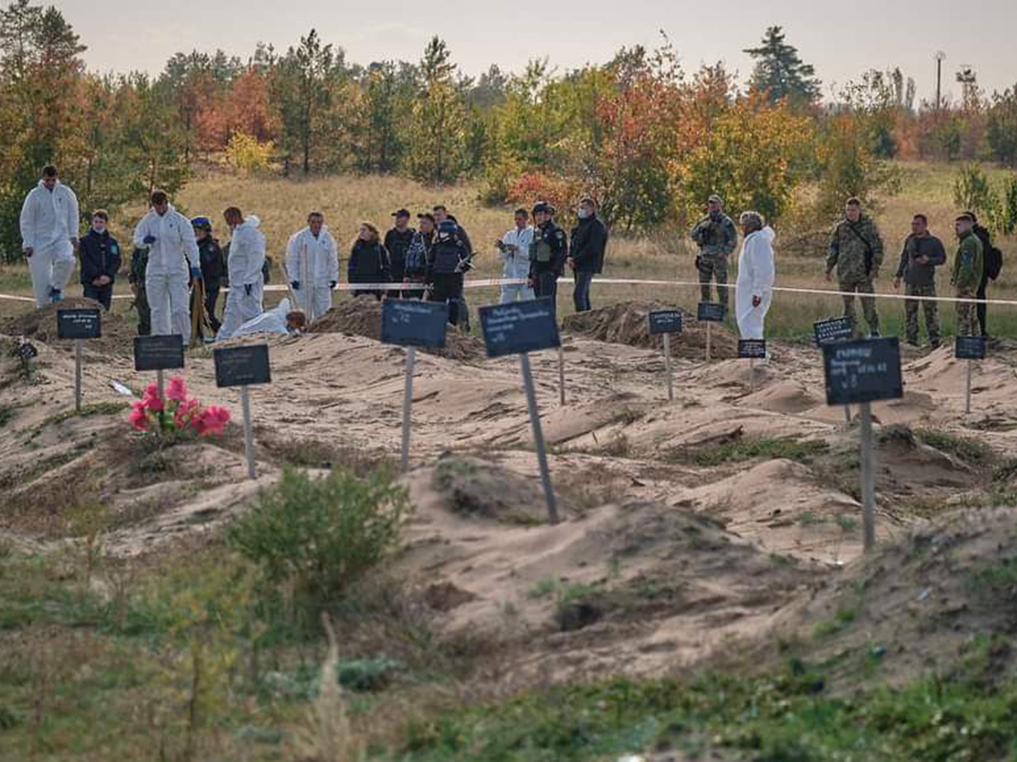 Forensic technicians and officers work at a burial site
