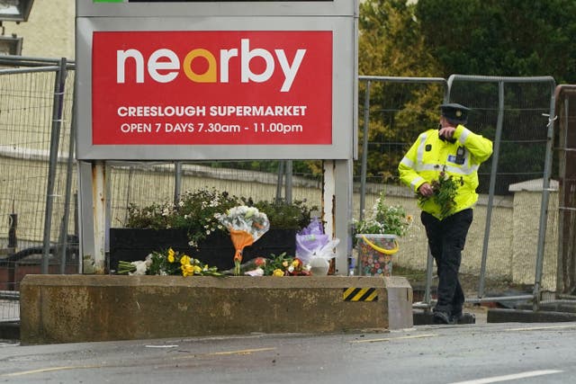 A member of An Garda brings flowers to the scene of the explosion (Brian Lawless/PA)