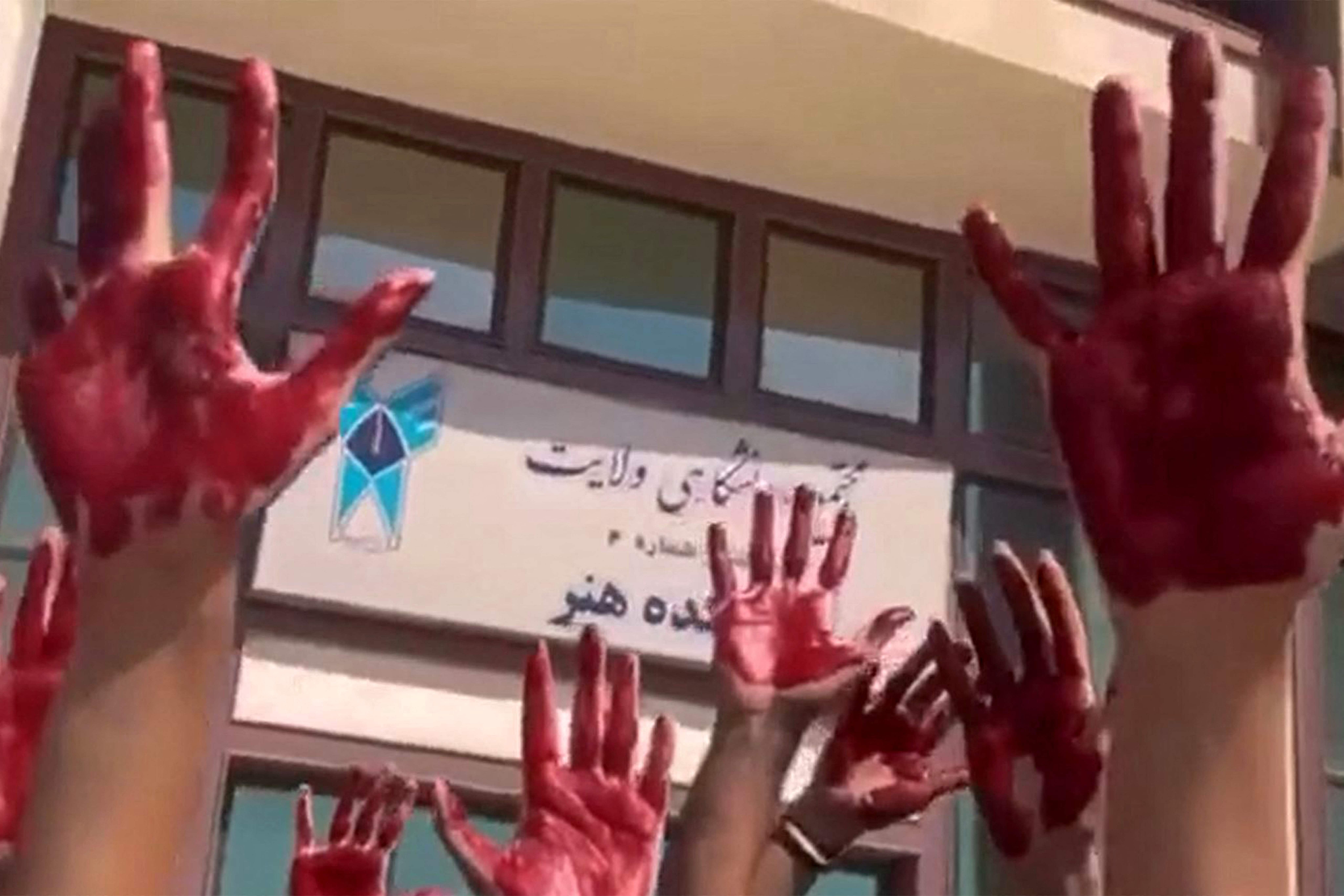 Iranian students from the Faculty of Arts at Tehran’s Azad University participate in a protest with their palms covered in red paint