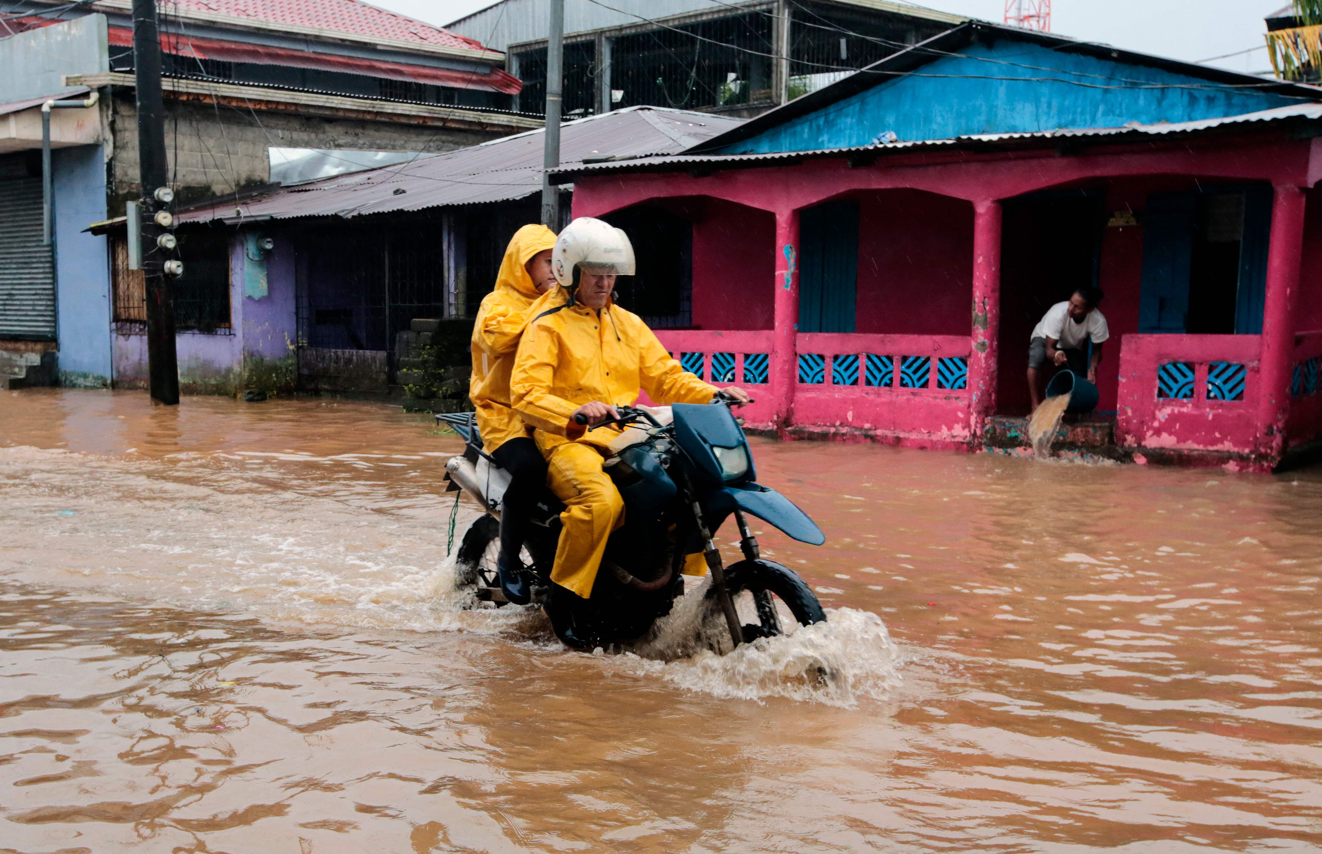 People ride a motorbike through flooded streets in Bluefields, Nicaragua on Sunday