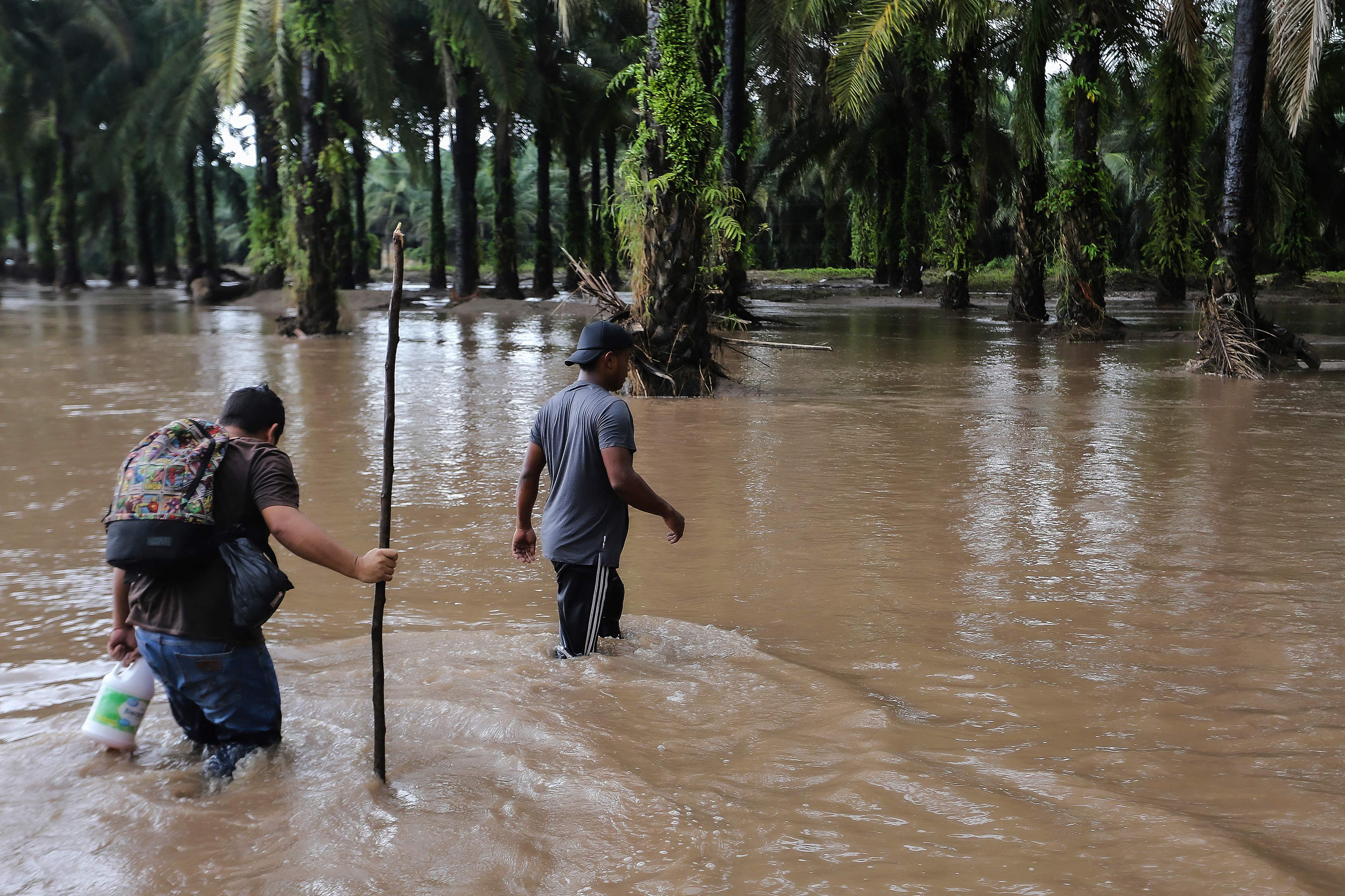 Two men walk though a flooded farm in Honduras after heavy rainfall from Hurricane Julia on Sunday