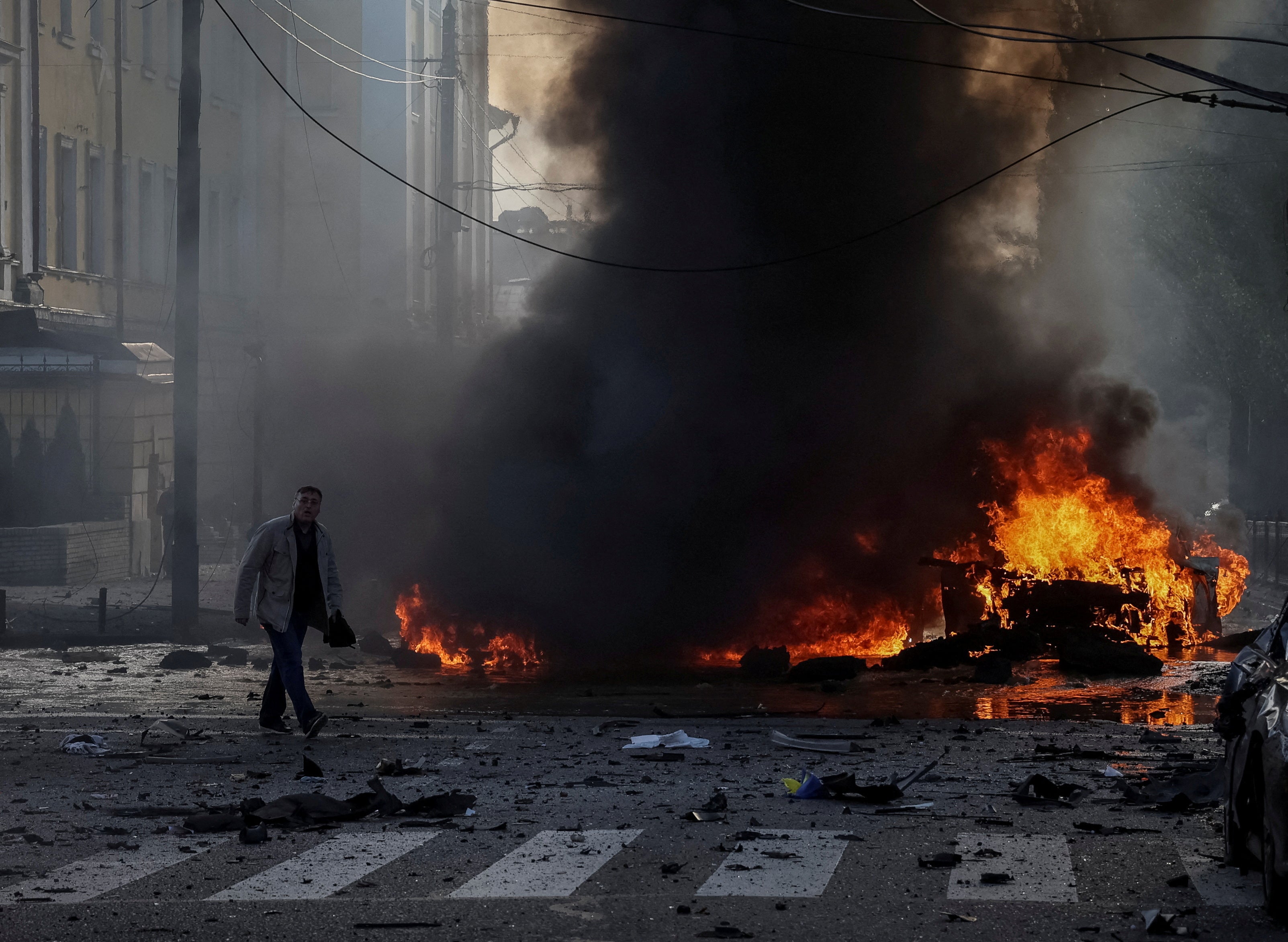 A driver walks near his burned car after a Russian military strike in Kyiv