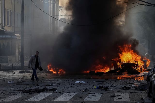 <p>A  driver walks near his burned car after a Russian military strike in Kyiv</p>