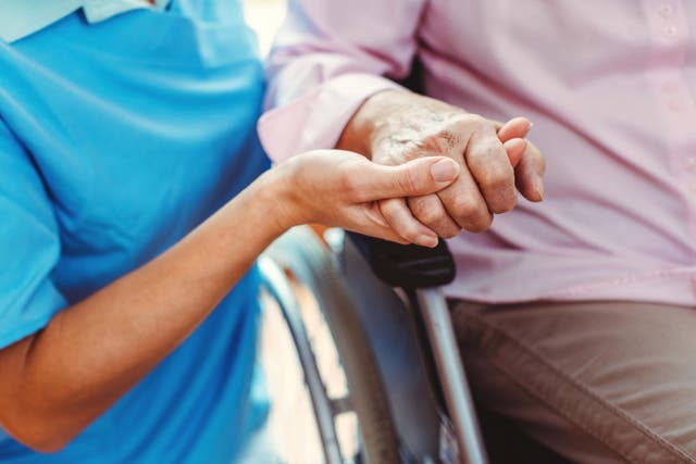 Nurse holding the hand of a woman in a nursing home (Kzenon/Alamy/PA)