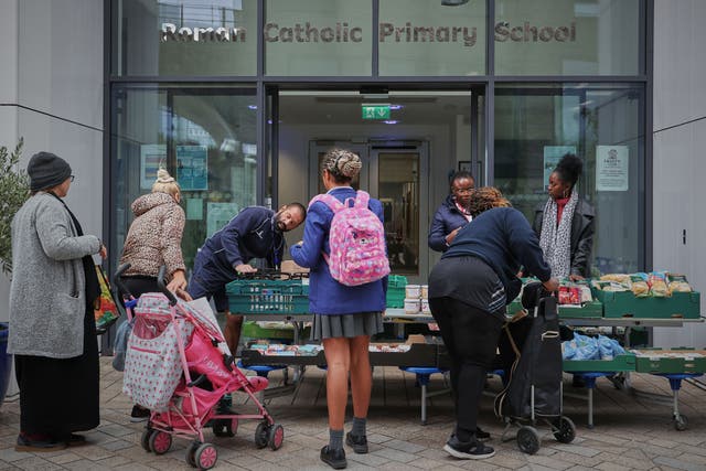 <p>Parents queue for food outside St Mary’s RC Primary School in Battersea, south London </p>