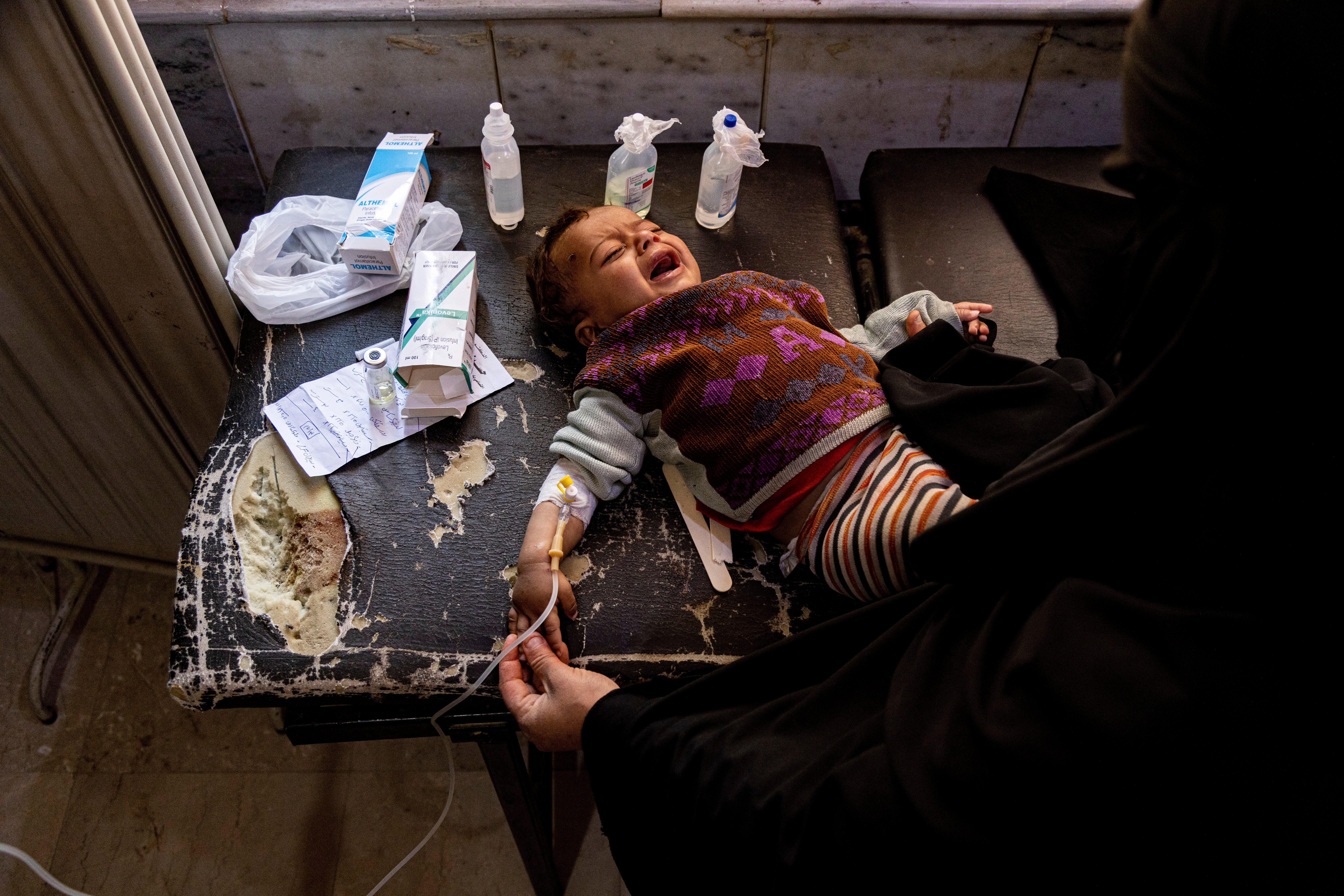A mother holds her child diagnosed with cholera in a hospital in Deir el-Zour, Syria