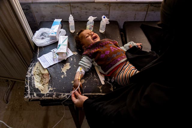 <p>A mother holds her child diagnosed with cholera in a hospital in Deir el-Zour, Syria</p>