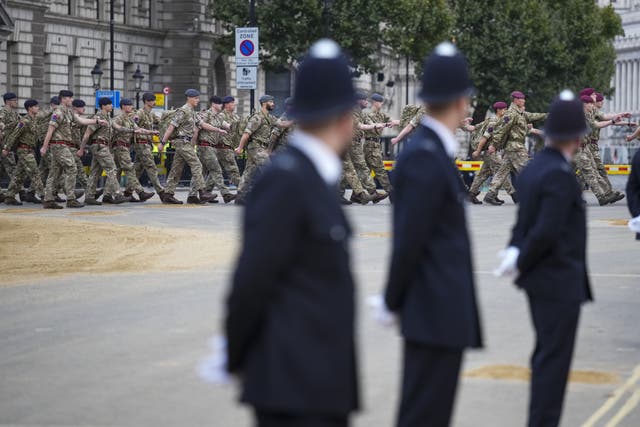 Police watch as armed forces personnel march into position in London ahead of the Queen’s funeral (Emilio Morenatti/PA)