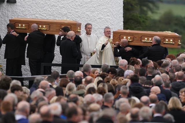 Priest Fr John Joe Duffy sprinkles holy water on the coffins of James Monaghan and his mother Catherine O’Donnell (Brian Lawless/PA)