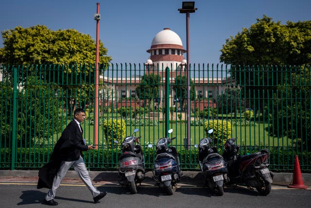 <p>File: A lawyer walks past the Supreme Court of India </p>