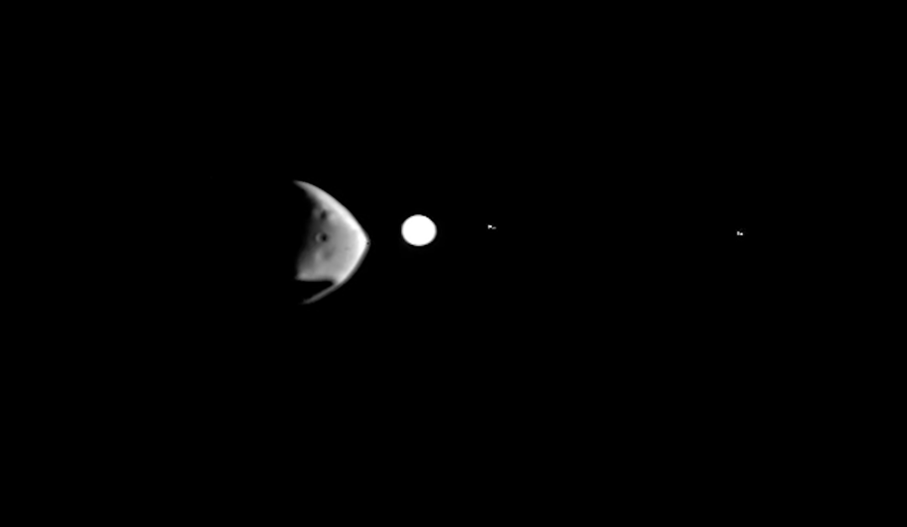 <p>The Martian moon Deimos, the lumpy shape in the foreground, is about to eclipse the bright white disk of distant Jupiter in this image taken by the ESA Mars Express orbiter in February, 2022</p>