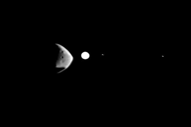 <p>The Martian moon Deimos, the lumpy shape in the foreground, is about to eclipse the bright white disk of distant Jupiter in this image taken by the ESA Mars Express orbiter in February, 2022</p>