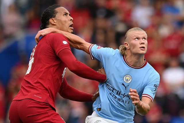 <p>Liverpool defender Virgil van Dijk challenges for the ball with Manchester City striker Erling Haaland</p>