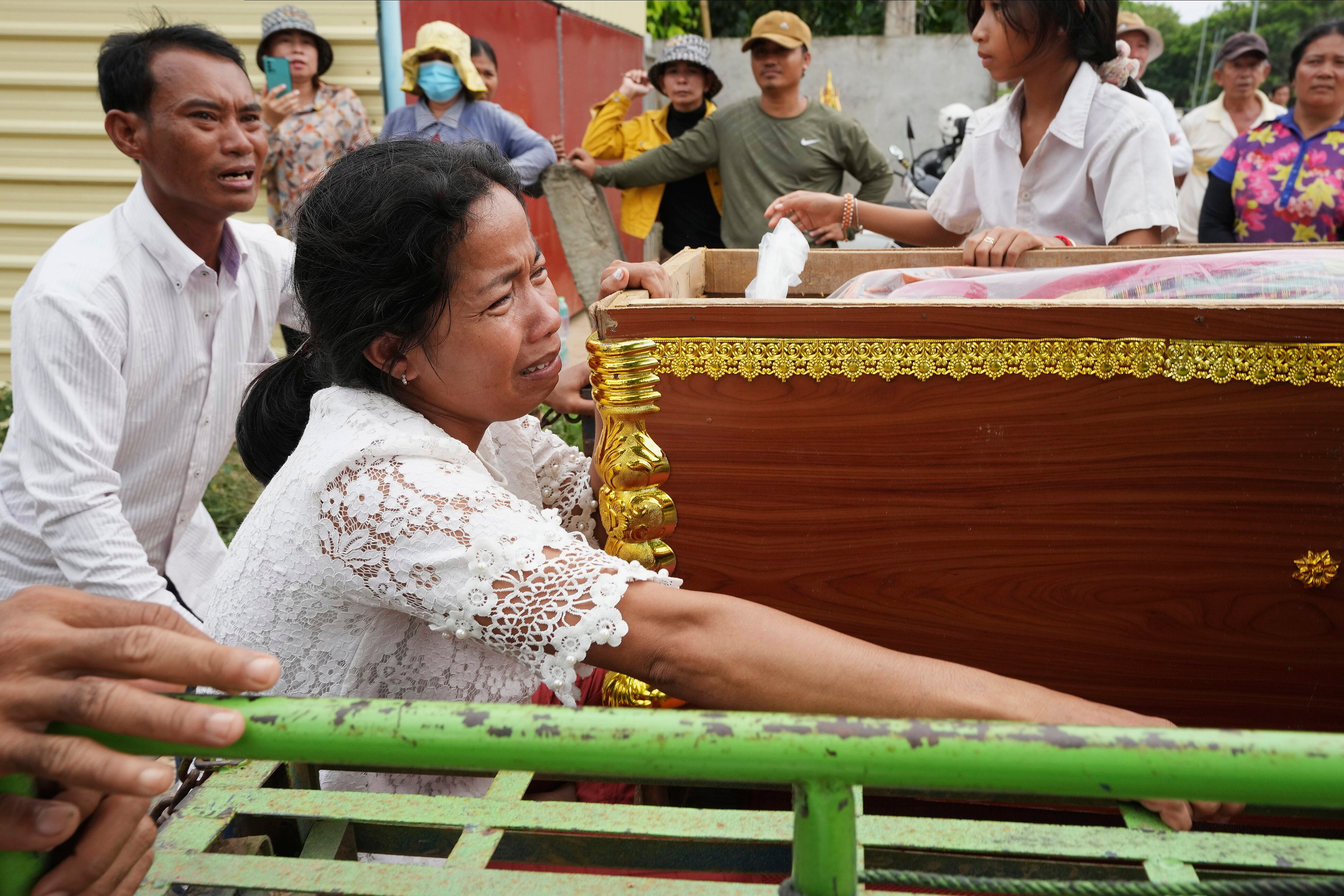 Mother of Son Sophat, a teen victim of a boat accident, cries by her daughter’s coffin during a funeral procession