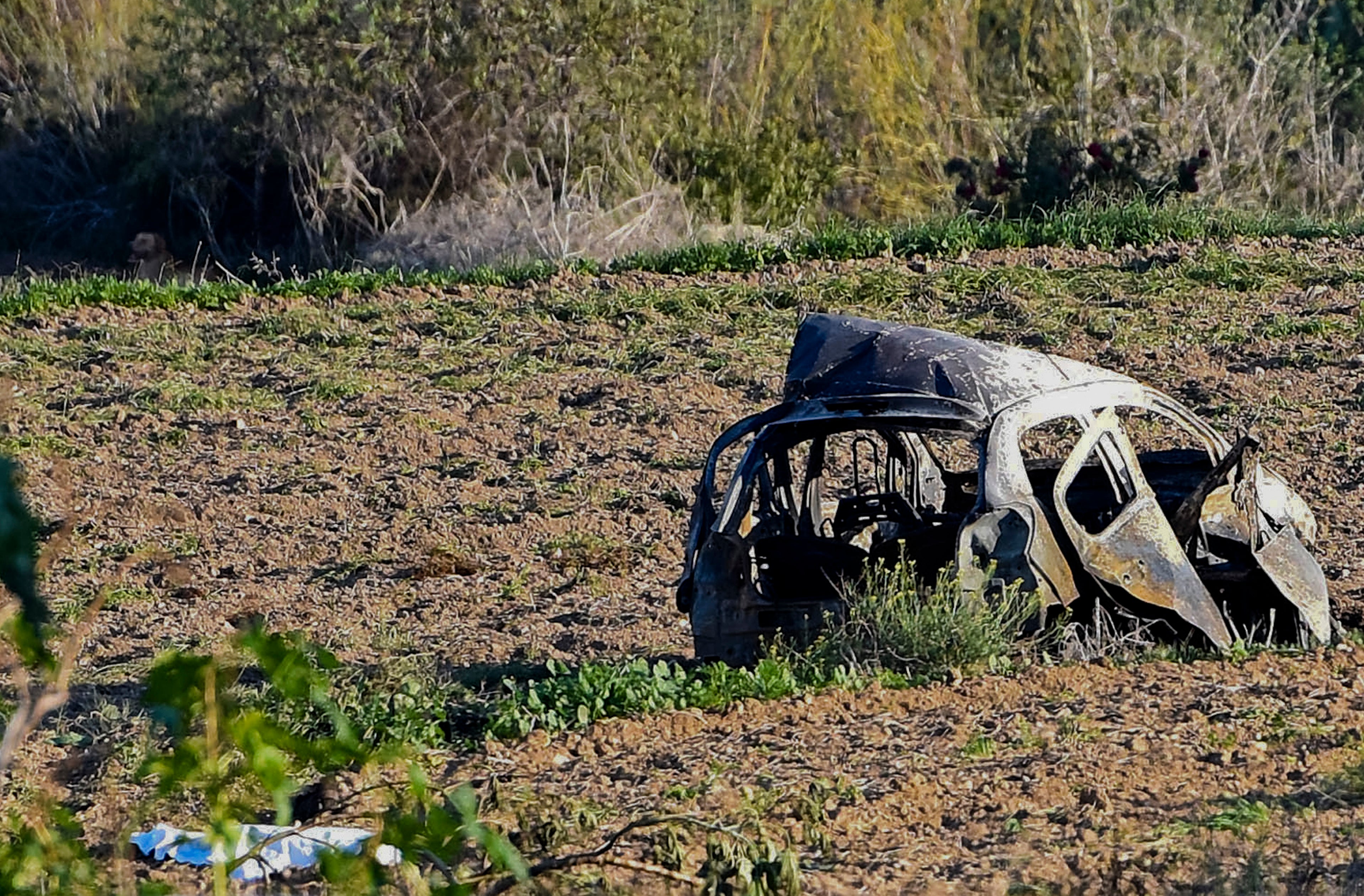 FILE - The wreckage of the car of investigative journalist Daphne Caruana Galizia lies next to a road in the town