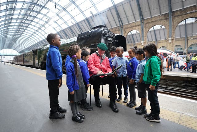 Sir Michael Morpurgo gives a reading to school children on Platform 8 at King’s Cross Station in London at the launch of the Flying Scotsman’s centenary campaign (James Manning/PA)
