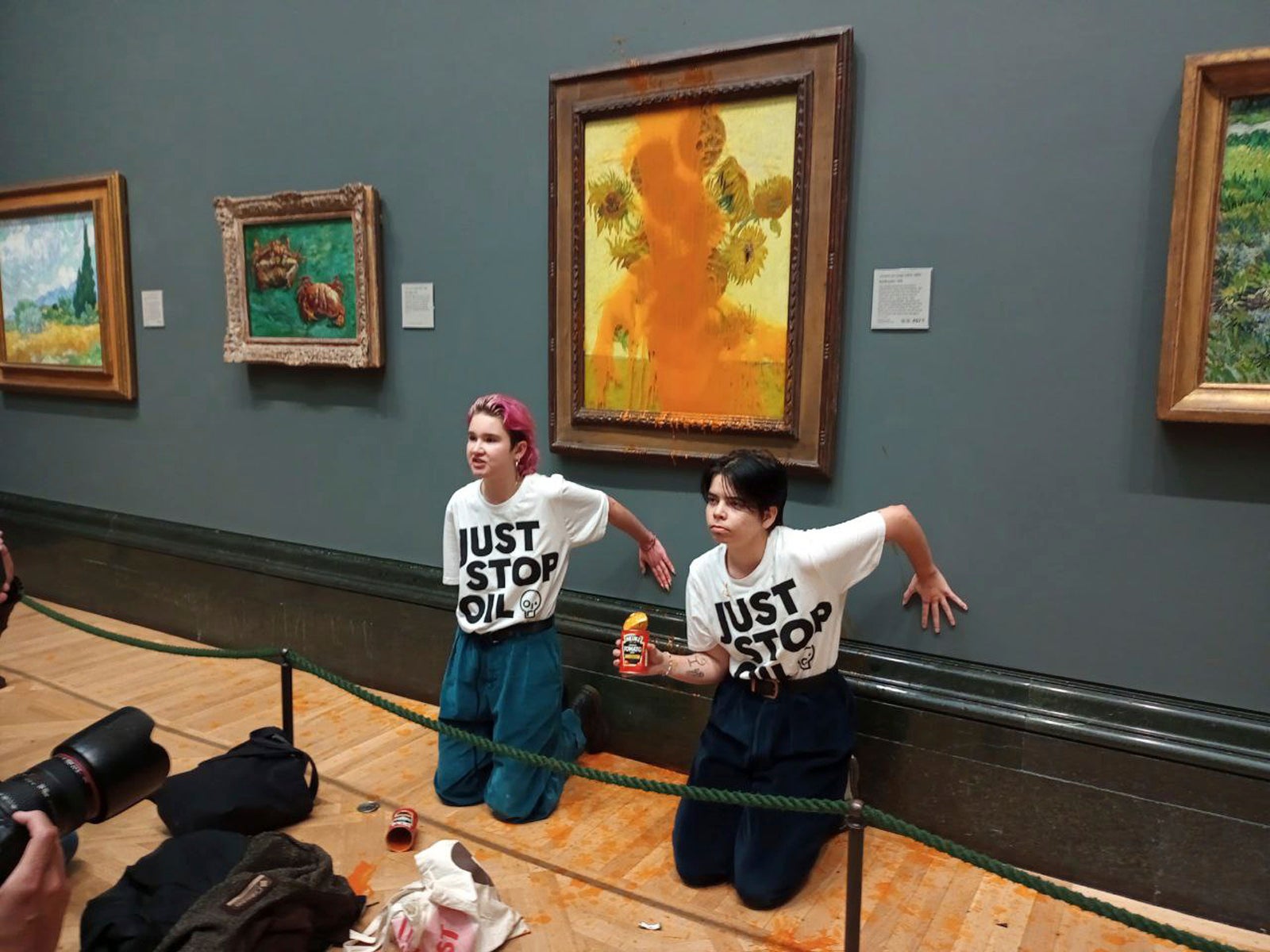Just Stop Oil protesters glued themselves to the wall after throwing tinned soup at Vincent Van Gogh's famous 1888 work ‘Sunflowers’ at the National Gallery in London on October 14