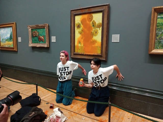<p>Just Stop Oil protesters glued themselves to the wall after throwing tinned soup at Vincent Van Gogh's famous 1888 work ‘Sunflowers’ at the National Gallery in London on October 14 </p>