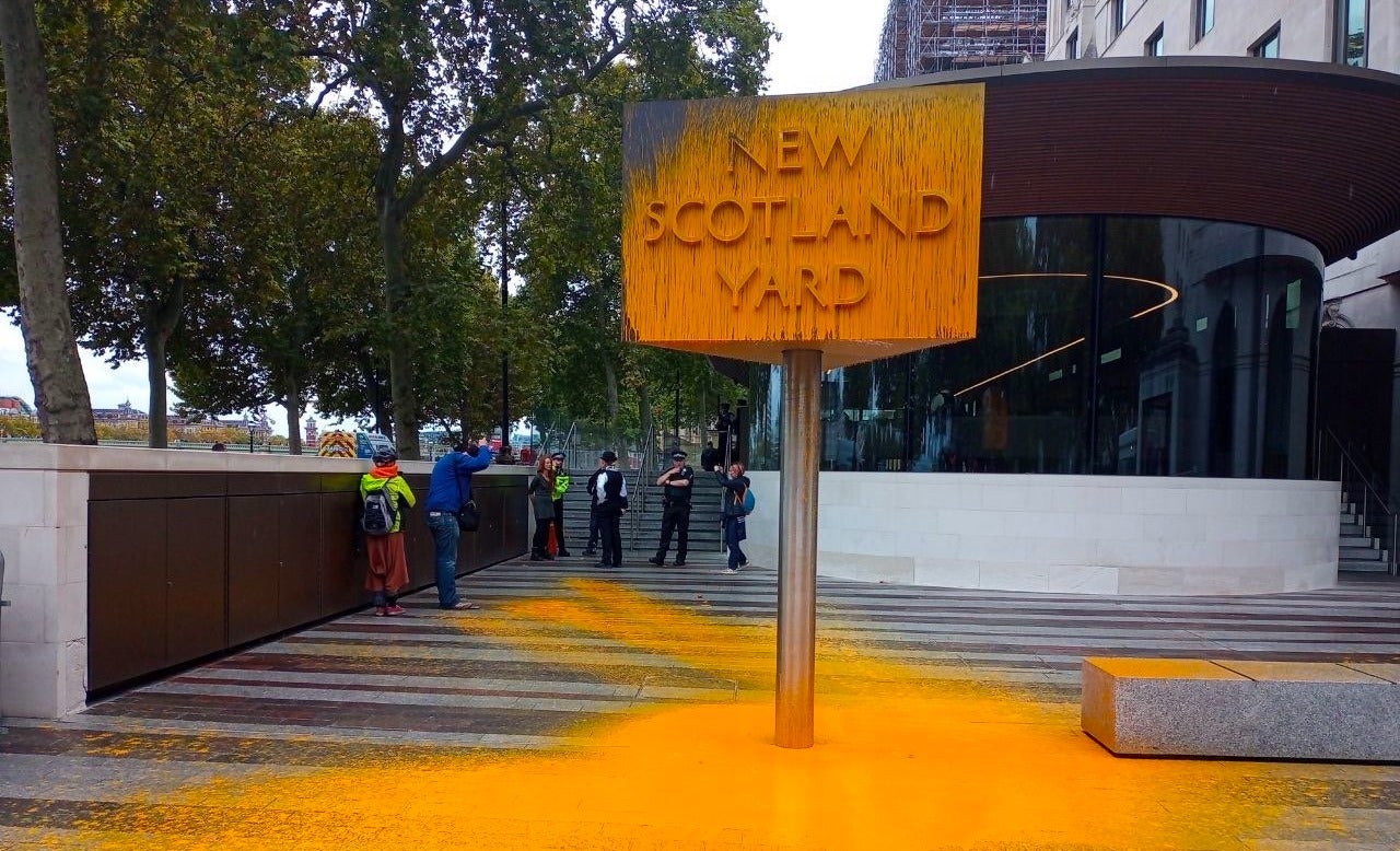 Just Stop Oil supporters spray paint sign at New Scotland Yard.