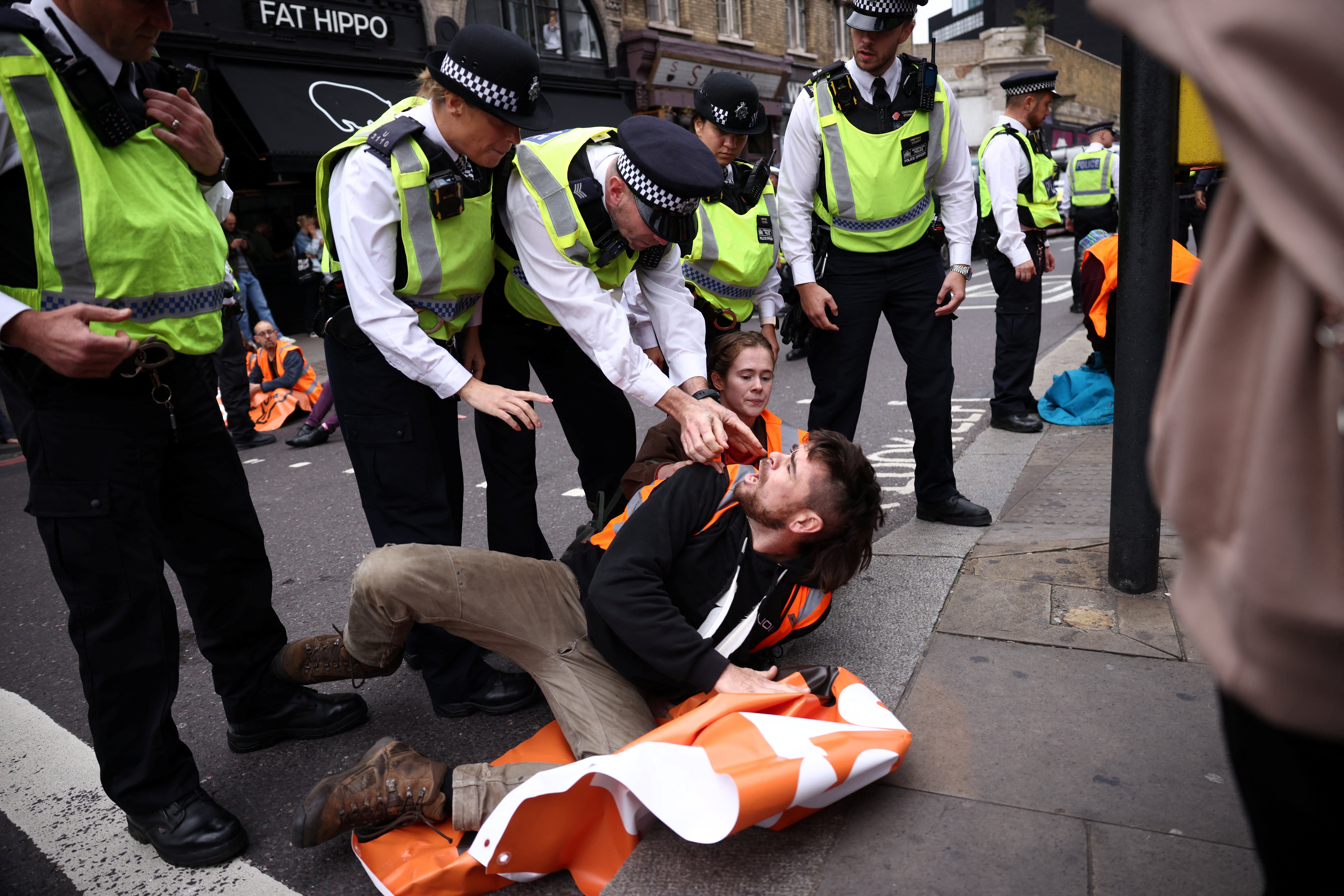 Police tackle an activist blocking the road in Shoreditch