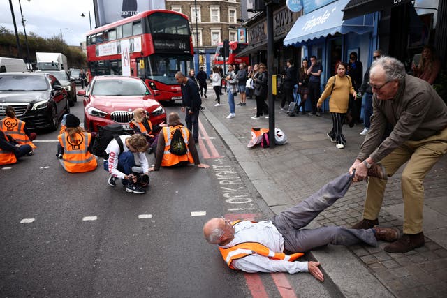 <p>A member of the public drags an activist blocking the road at a ‘Just Stop Oil’ demonstration in Shoreditch, east London</p>