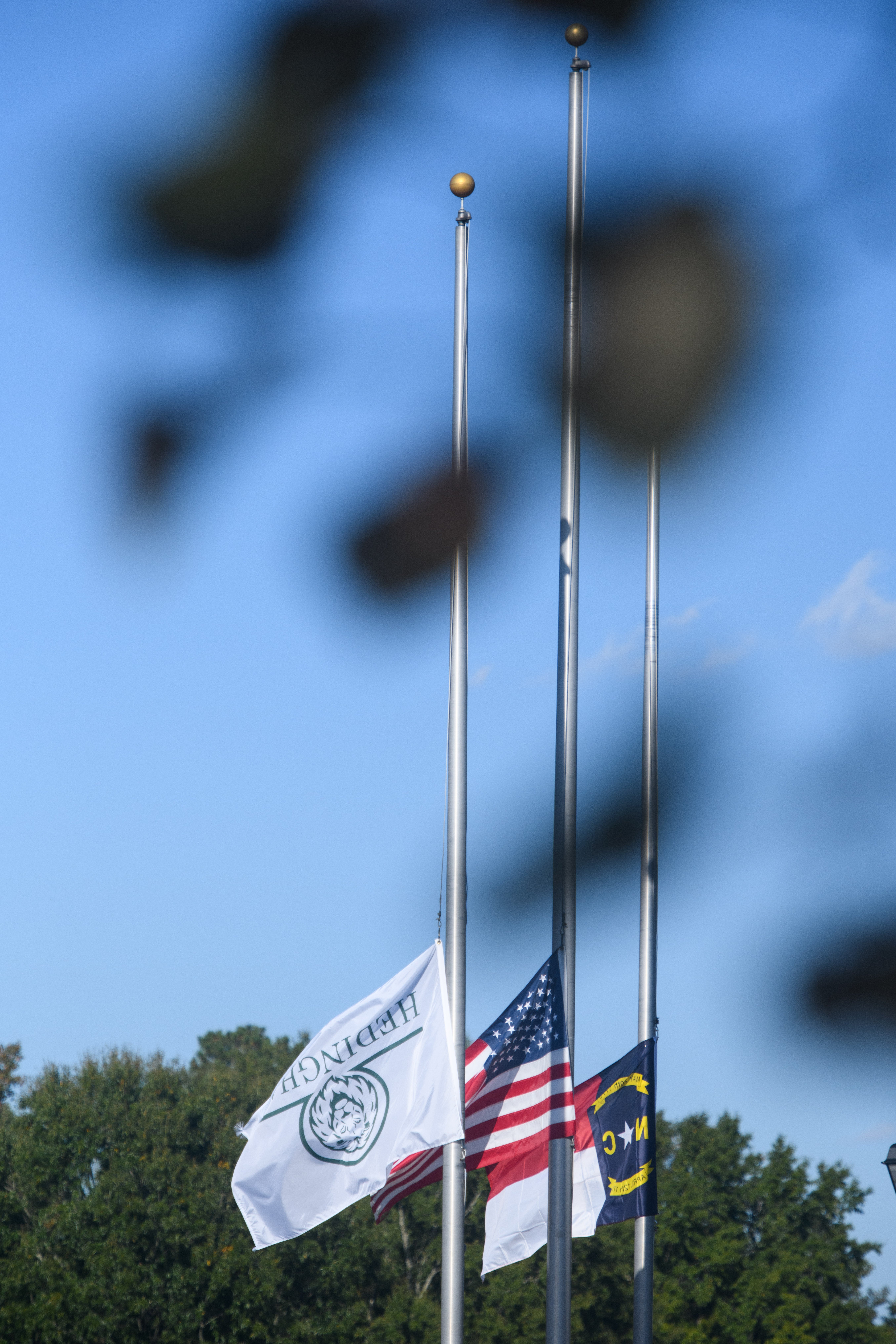 An American flag and a Hedingham neighborhood flag fly at half-staff on October 14, 2022 in Raleigh, North Carolina in honor of 5 victims of a mass shooting that occurred in and around the neighborhood