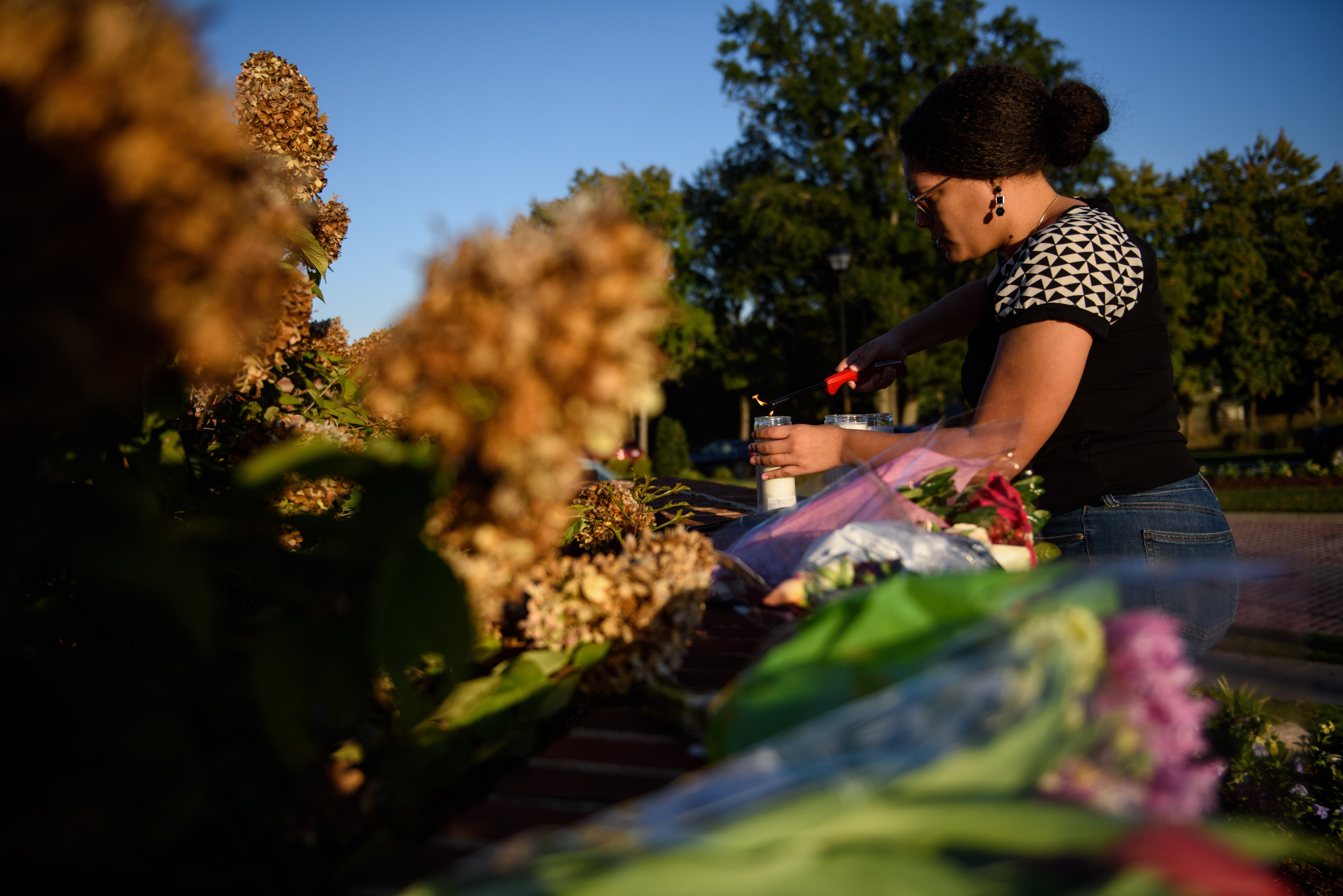 A woman lays flowers and lights candles at the entrance of Hedingham neighborhood on October 14, 2022 in Raleigh, North Carolina