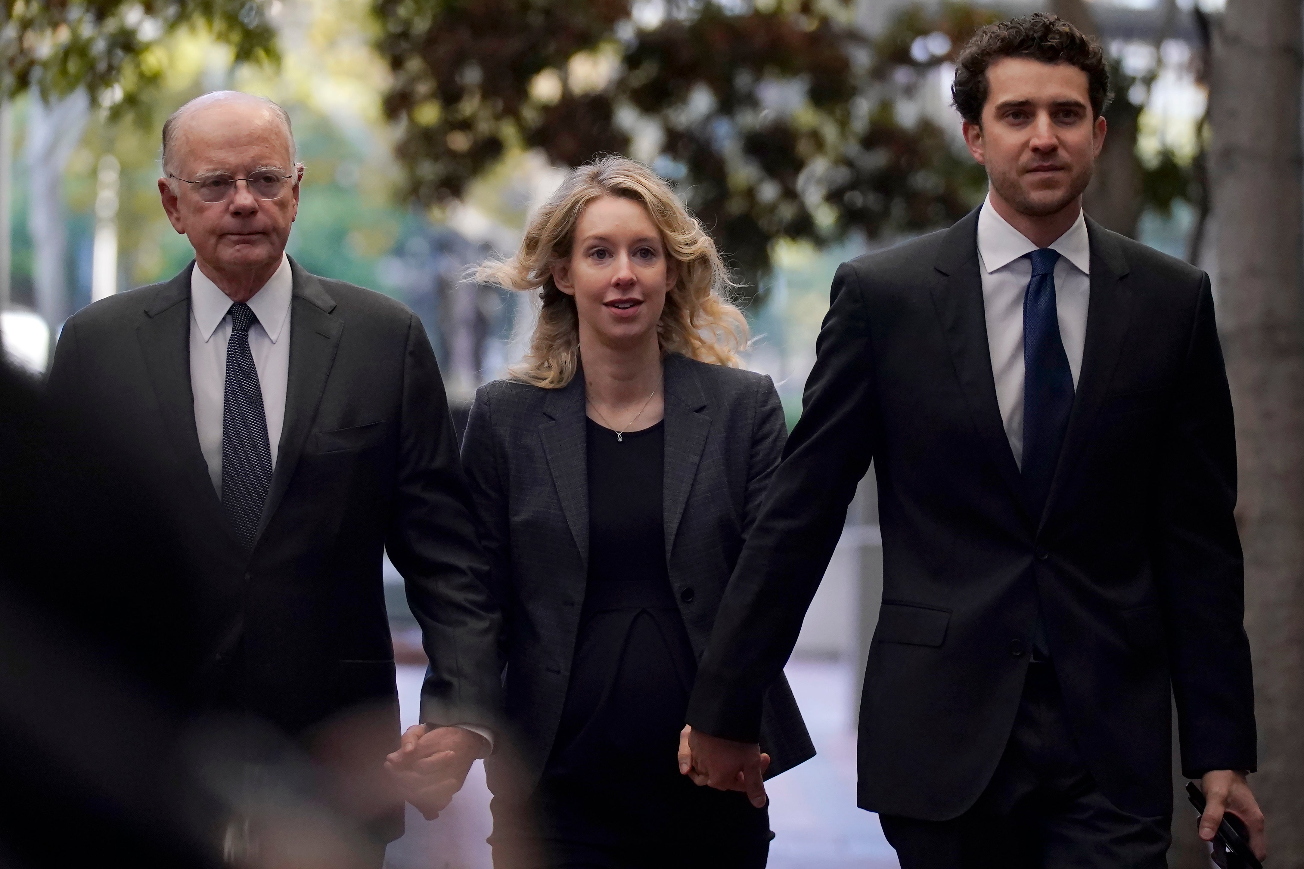 Former Theranos CEO Elizabeth Holmes, center, arrives at federal court with her father, Christian Holmes IV, at trial in 2022.