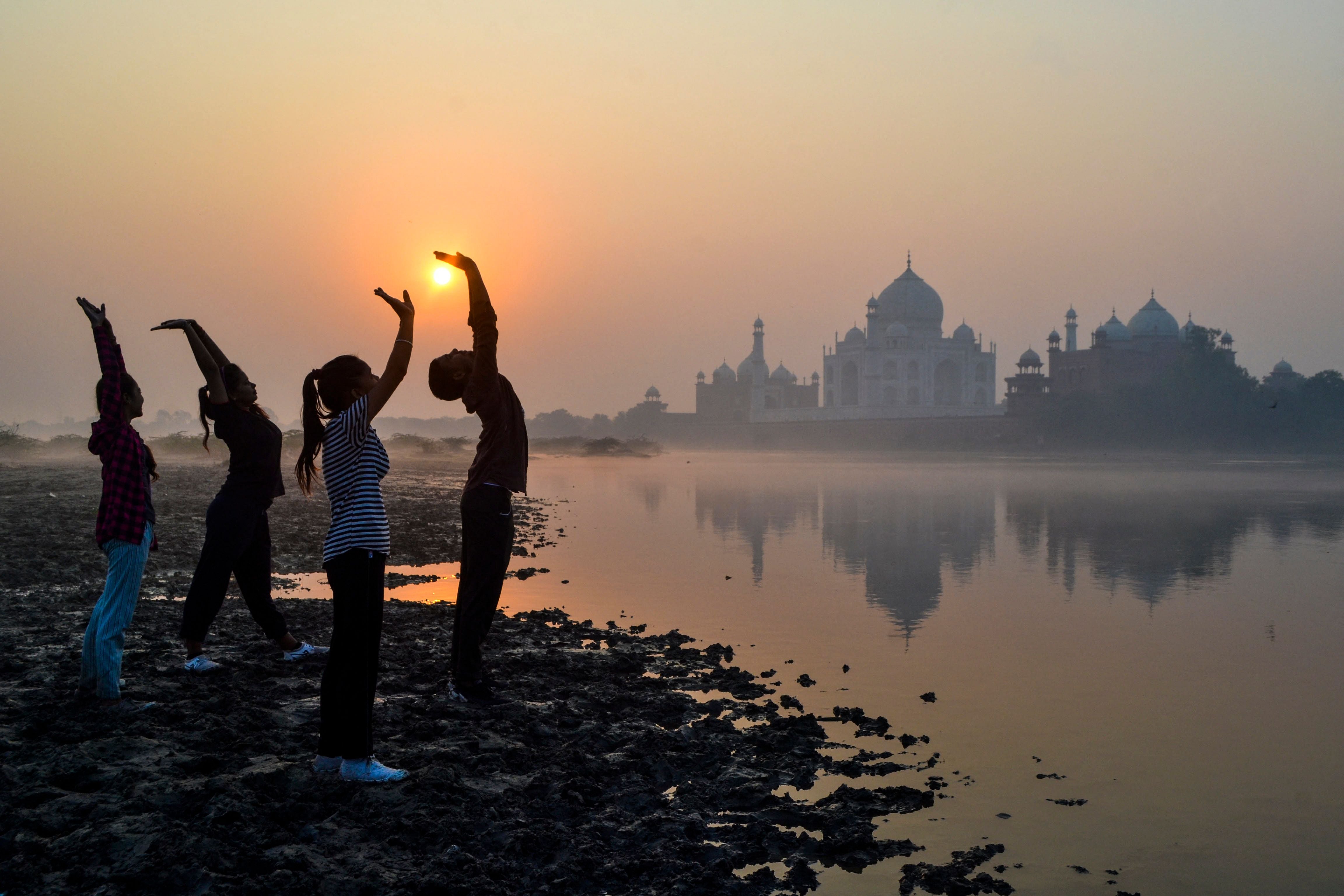 Children exercise on the banks of the Yamuna River near the Taj Mahal in Agra at sunrise