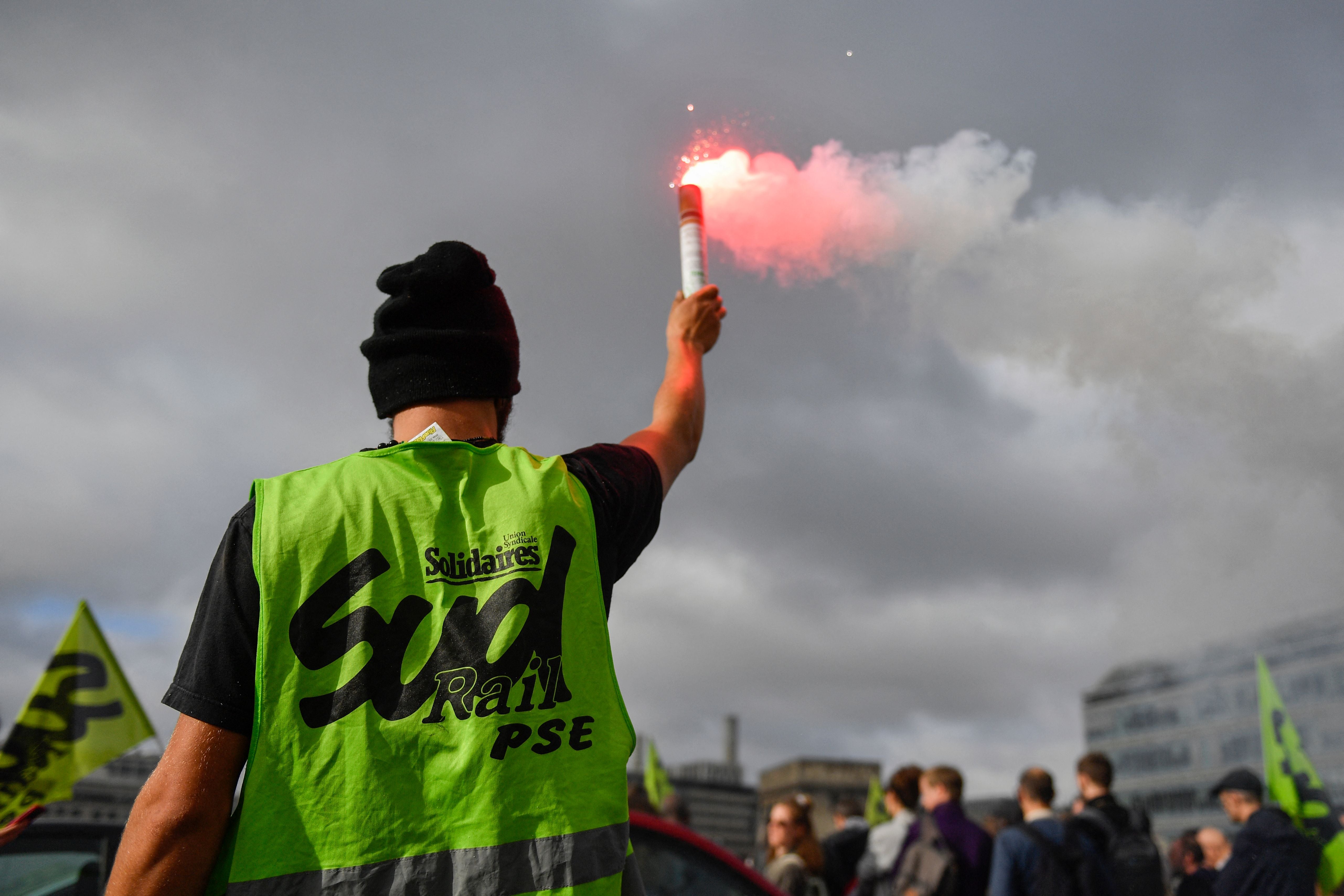 A railway worker lights a flare as he attends a general assembly of railway workers in Gare de Lyon, in Paris