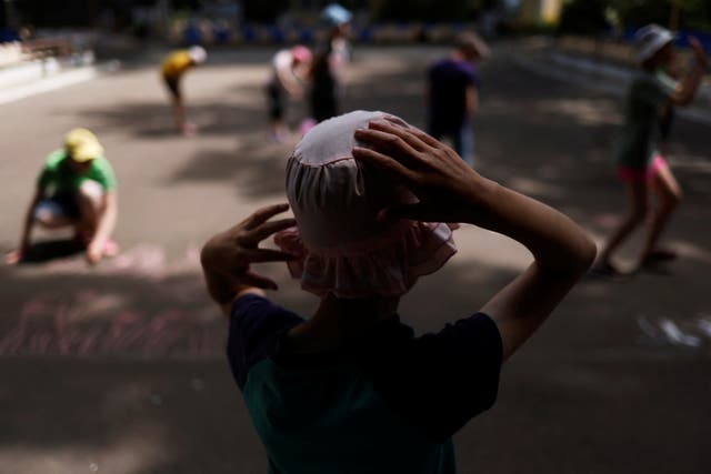 <p>Tanya, 12, who is autistic and does not speak, watches other children draw with chalk in a play area at a facility for people with special needs in Odesa, Ukraine</p>