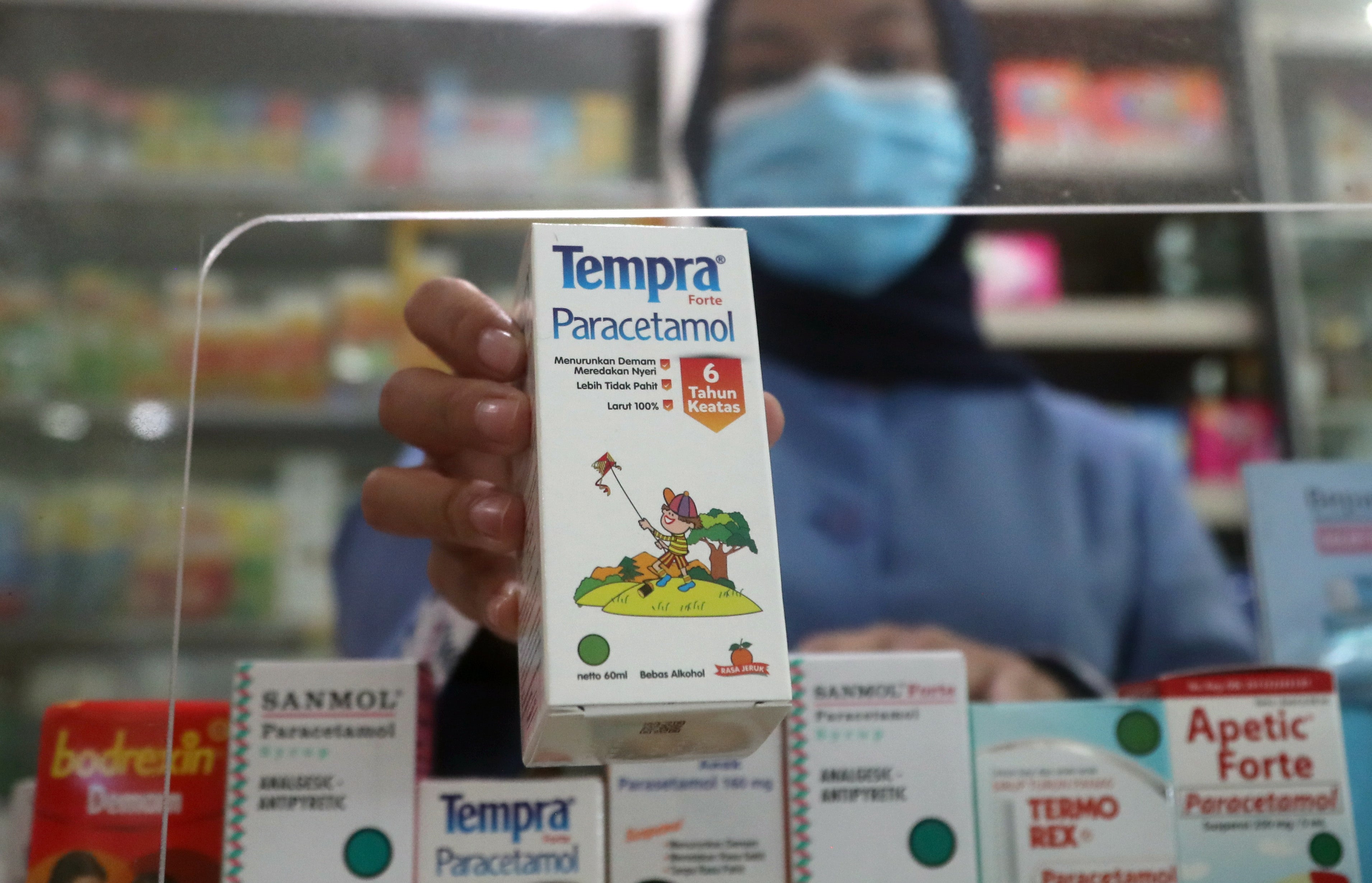 A pharmacist shows a paracetamol syrup for children as it is removed from the shelf in Depok, West Java, Indonesia