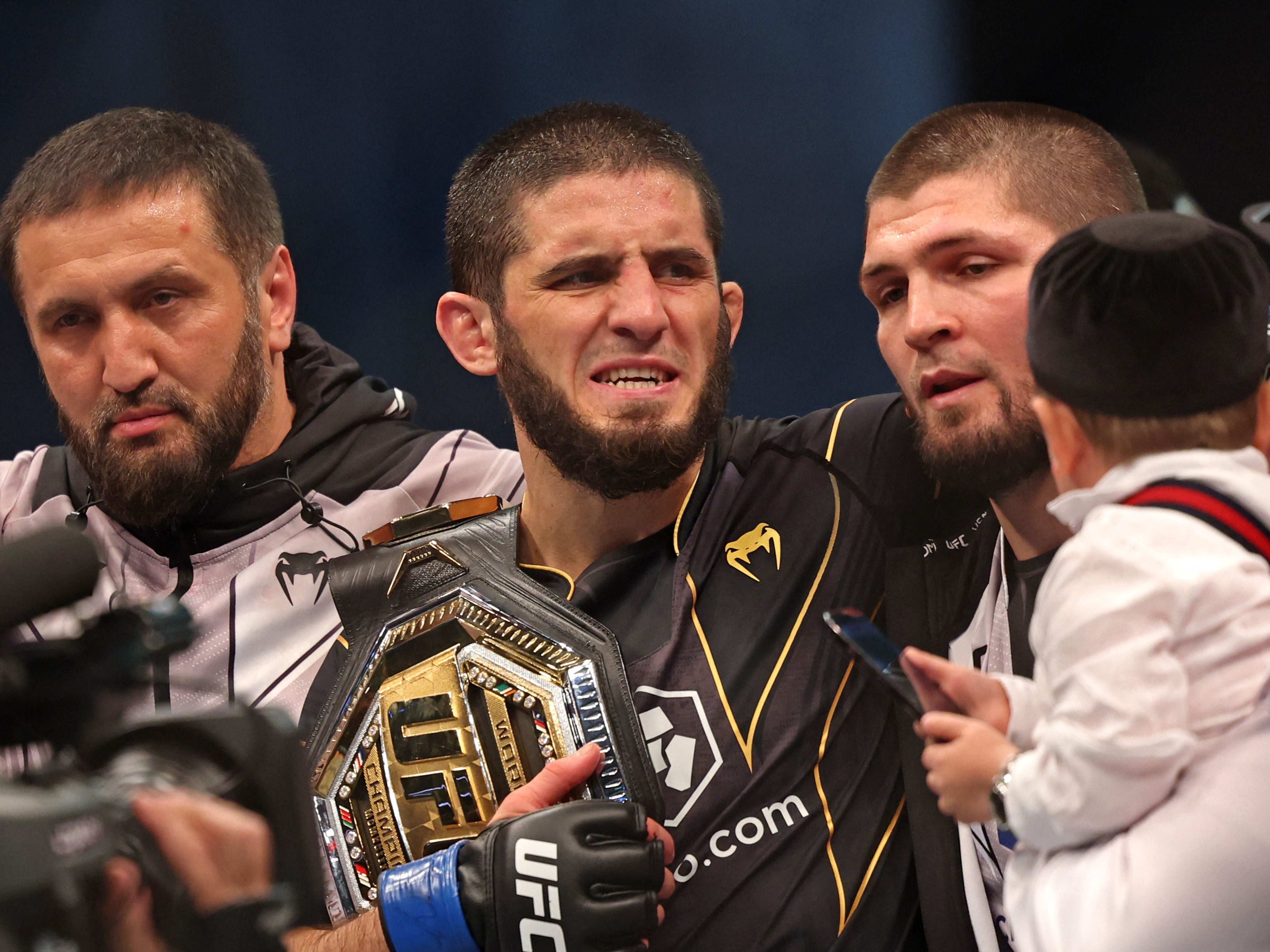 Islam Makhachev (centre) with Khabib Nurmagomedov (centre-right) after submitting Charles Oliveira to win the UFC lightweight title