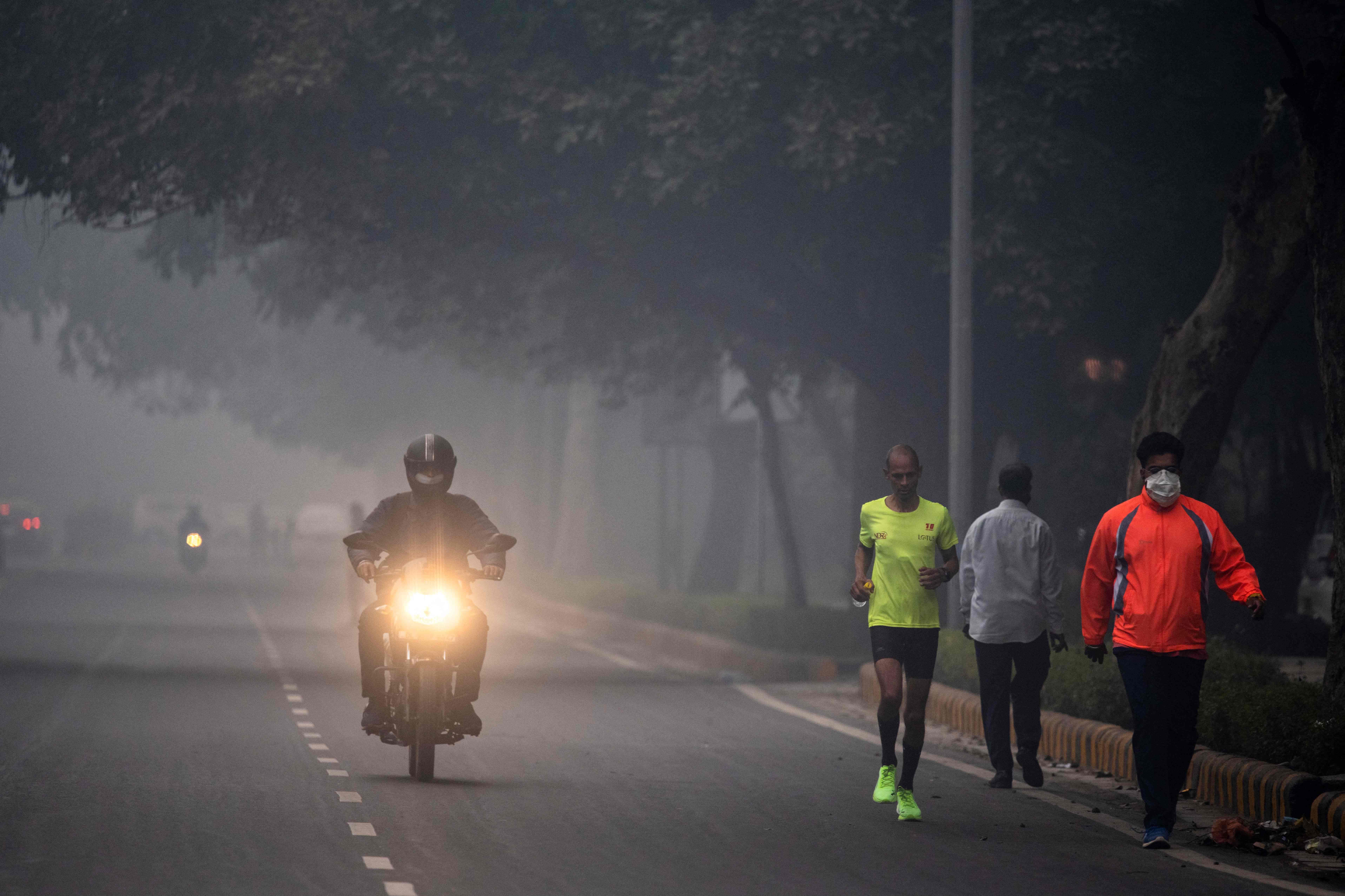 A man runs along a street amid smoggy conditions in New Delhi