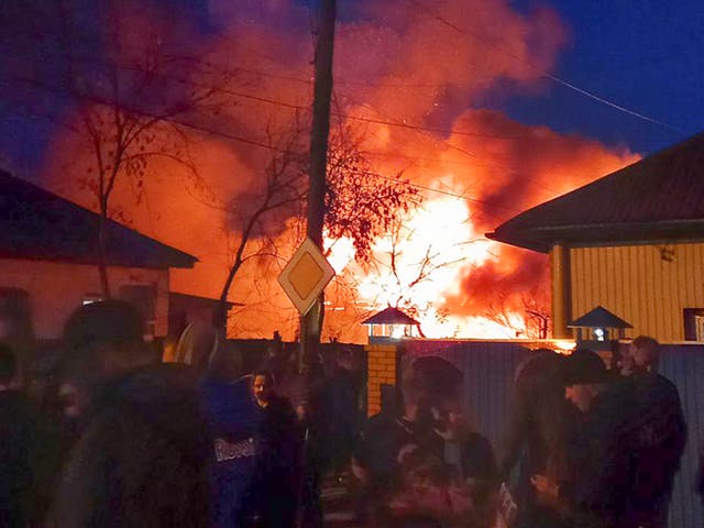 <p>Residents in the glow of flames left after a Russian warplane hit a residential building in Irkutsk</p>