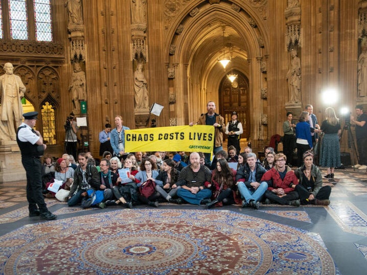 Climate and energy crisis activists unfurl a banner reading ‘Chaos costs lives’ in the Central Lobby in parliament