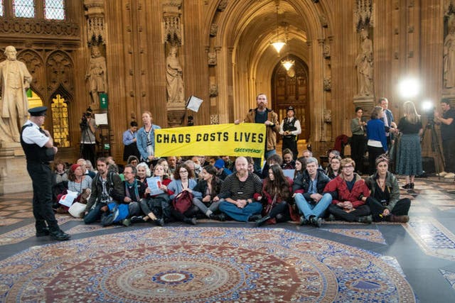 <p>Climate and energy crisis activists unfurl a banner reading ‘Chaos costs lives’ in the Central Lobby in parliament</p>