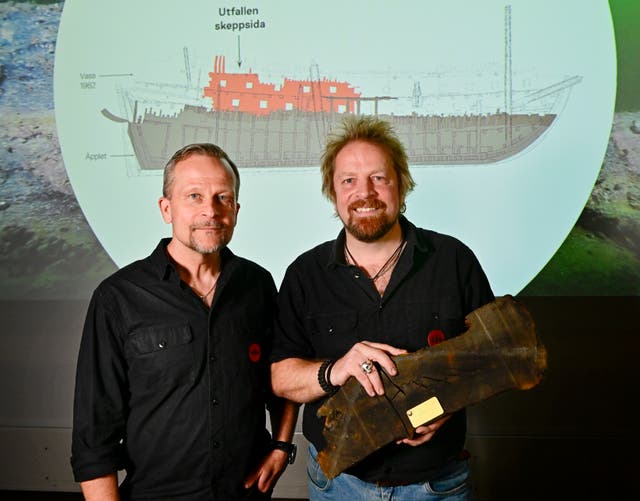 <p>Swedish archaeologists post with a piece of ship from the wreck of 17th-century shipwreck ‘Applet’</p>