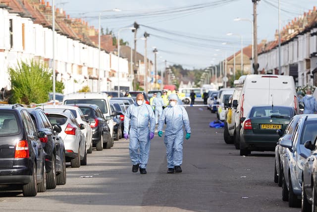 <p>Forensics officers at the scene in Ilford after two men died and a third was left critically injured after a shooting</p>